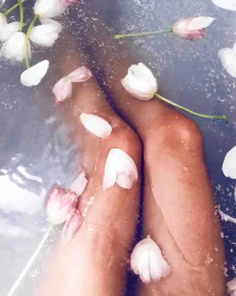 A close-up of smooth legs surrounded by flower petals, reflecting the care of professional Brazilian waxing.